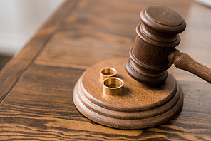 close-up view of judge hammer and wedding rings on wooden table, divorce concept