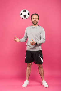 nale football player throwing up ball isolated on pink