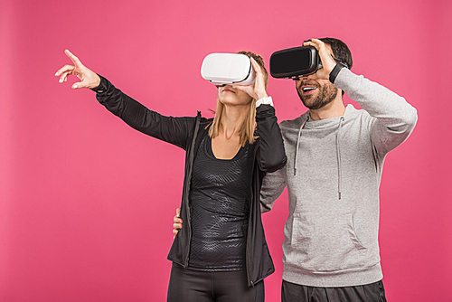 couple using virtual reality headsets, isolated on pink