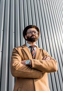 low angle view of businessman in glasses standing with arms crossed