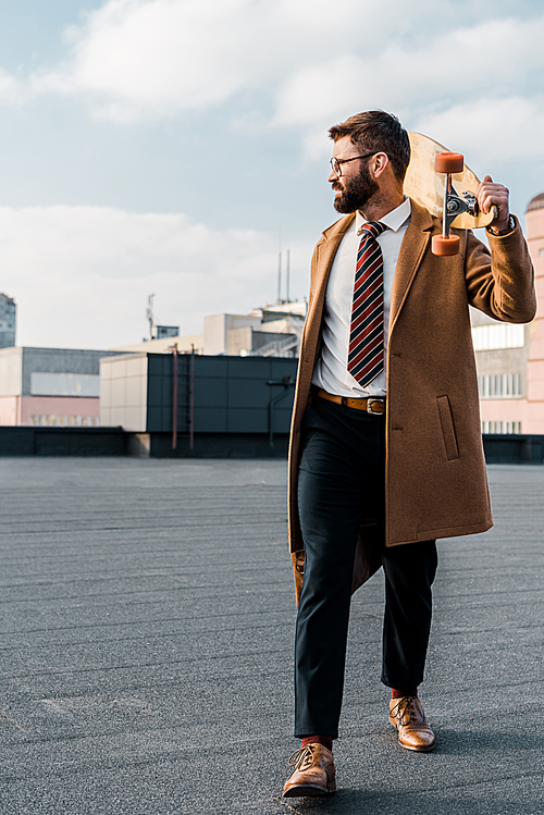 successful businessman in formalwear and coat walking with penny board