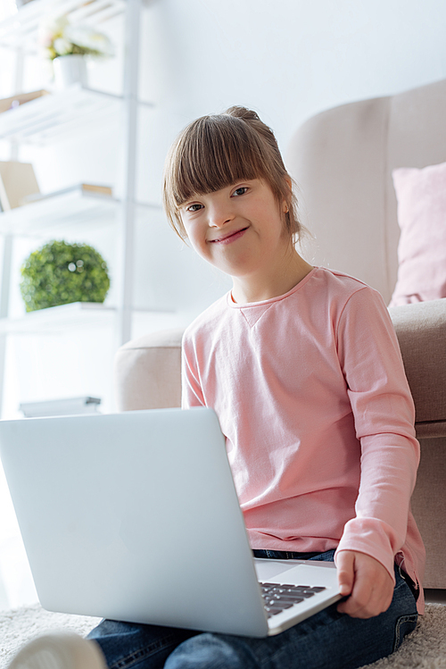 Smiling kid with down syndrome using laptop