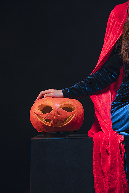 woman in red cloak with jack o lantern on dark background