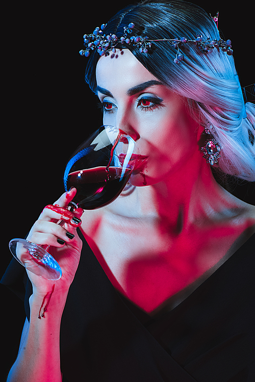 beautiful vampire drinking blood from wineglass isolated on black