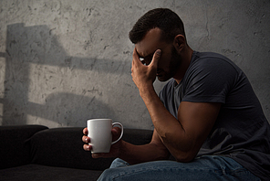 lonely crying man holding cup of coffee sitting at home