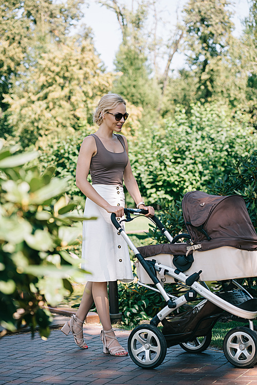 mother walking with baby carriage in park