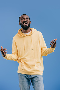 excited african american man gesturing by hands isolated on blue background