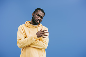 skeptical young african american man gesturing by hand isolated on blue background