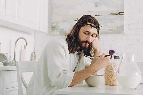 tired Jesus eating corn flakes on breakfast in kitchen at home