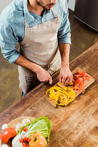 high angle view of man in apron cutting vegetables in kitchen