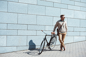 stylish middle aged man standing with bicycle and looking away on street