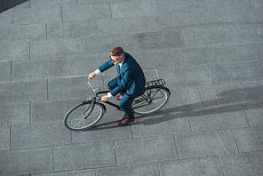 high angle view of middle aged businessman in suit and eyeglasses riding bicycle on street