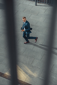 high angle view of businessman holding coffee to go and walking on street