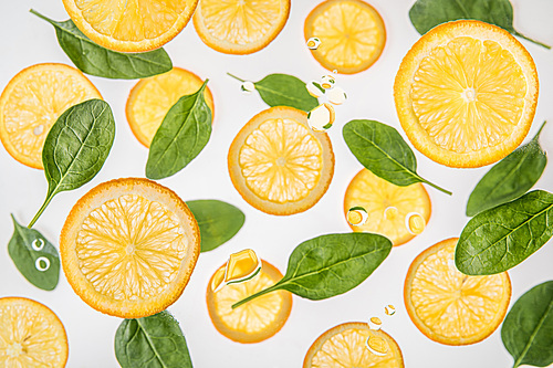 fresh juicy orange slices with green spinach leaves on grey background with water bubbles