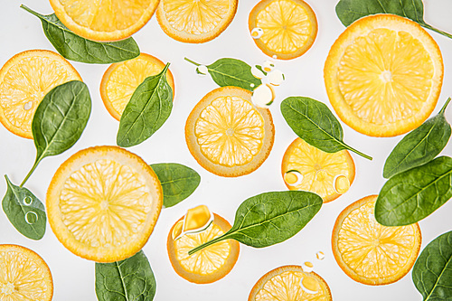 juicy orange slices with green spinach leaves on grey background