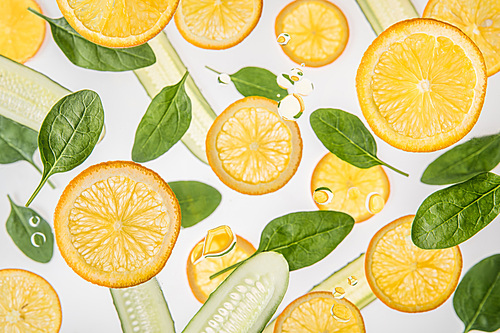 fresh orange slices with green spinach leaves and cucumbers on grey background