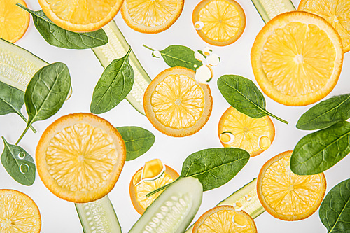 orange slices with green spinach leaves and cucumbers on grey background