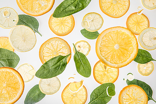 bright orange and lemon slices with green spinach leaves on grey background