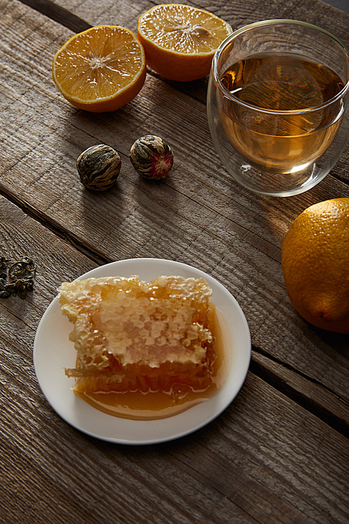 glass of traditional chinese blooming tea, lemons and honeycomb on wooden table