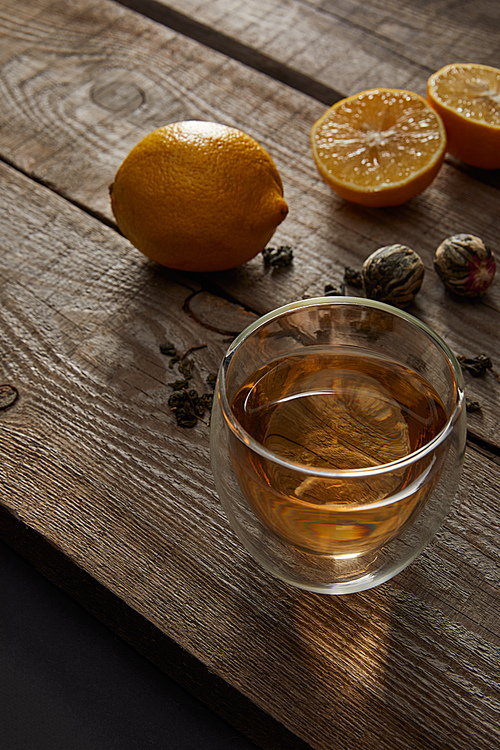 glass of traditional chinese blooming tea and lemons on wooden table