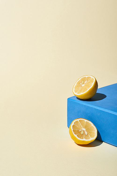 bright lemon halves and blue cube on beige background