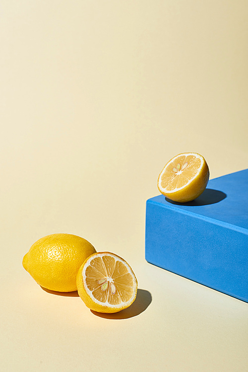yellow bright lemons near blue cube on beige background