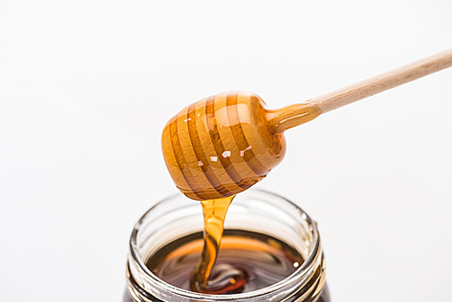 jar with honey and wooden honey dipper isolated on white