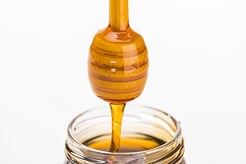 wooden honey dipper with dripping honey isolated on white