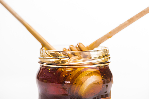 jar with honey and wooden honey dippers isolated on white with copy space