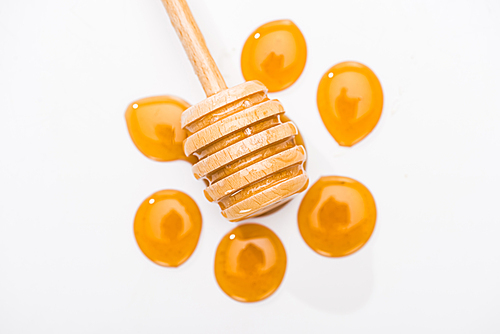 top view of honey drops and wooden honey dipper isolated on white