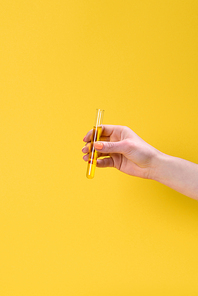 cropped shot of woman holding flask of liquid isolated on yellow