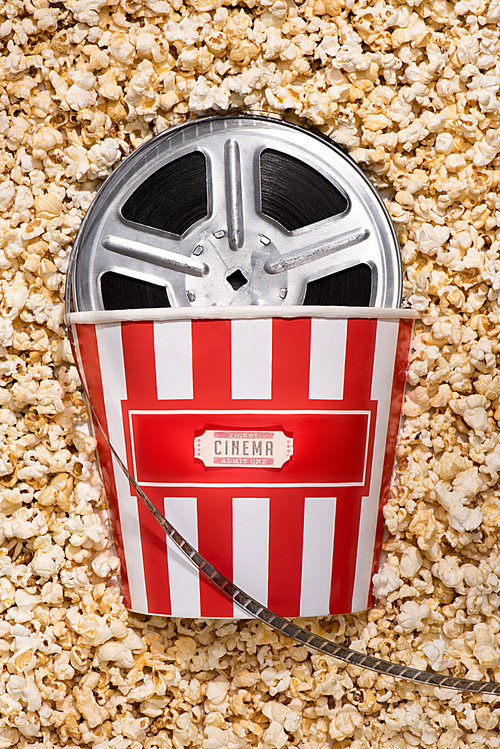 flat lay with disposable bucket, popcorn, retro cinema ticket and filmstrips