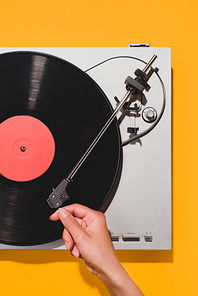 cropped shot of woman turning on vinyl player isolated on yellow