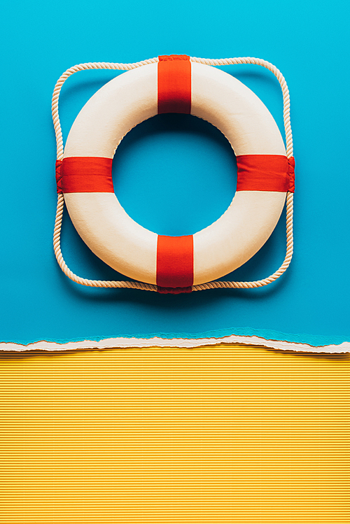 top view of red and white life saver on blue and yellow paper background