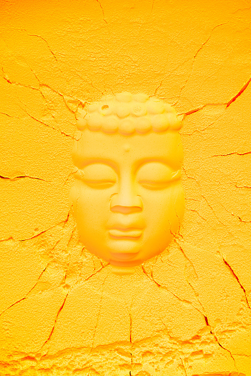 top view of buddha head shape on orange flour texture with cracks