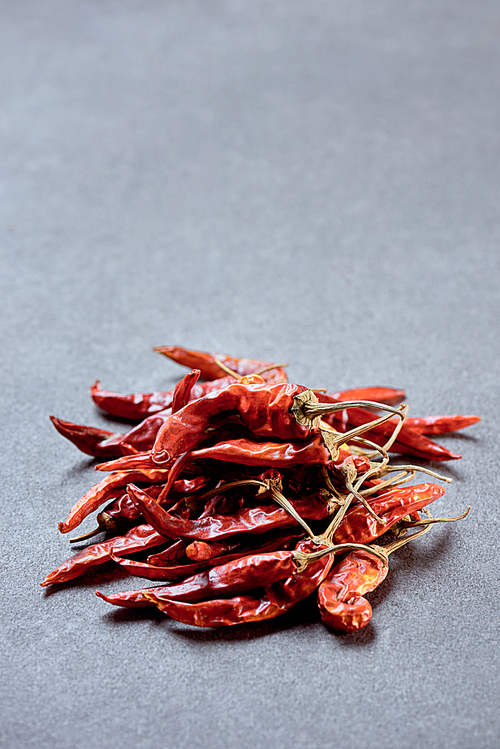close up view of pile of red chili peppers on grey surface