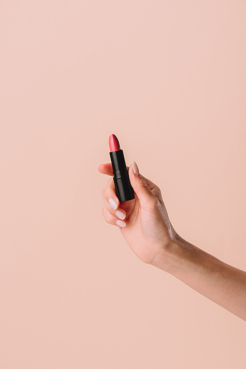 cropped shot of woman holding lipstick isolated on beige