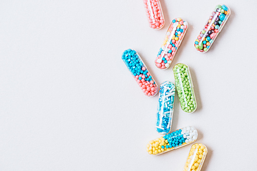 top view of different colorful medical capsules on white surface