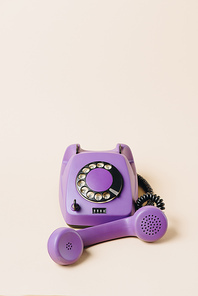 purple vintage rotary telephone with tube on beige