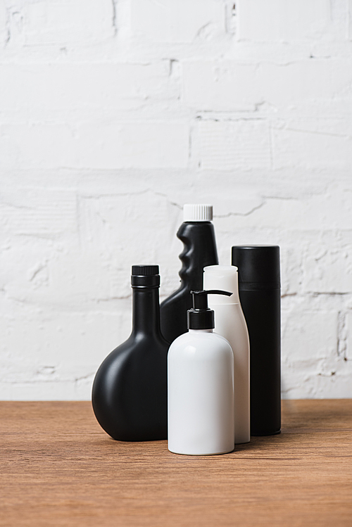Black and white plastic bottles on wooden table on brick wall background