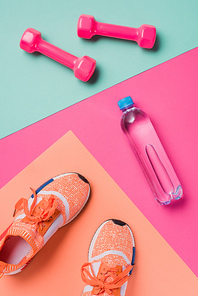 Flat lay with sneakers, dumbbells and sport bottle on colorful background