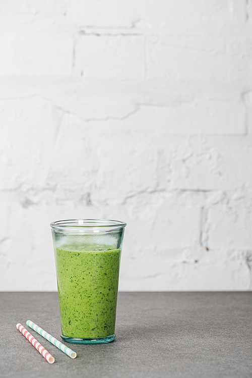 Mixed green organic smoothie in glass with straws