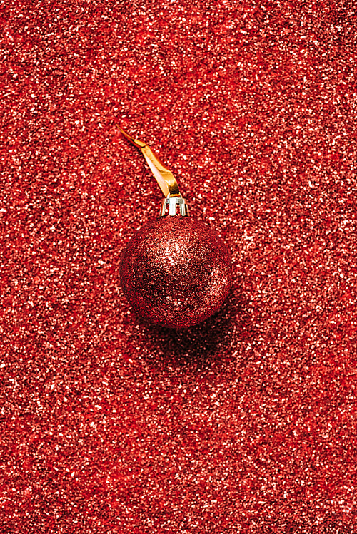 top view of red shiny decorative christmas ball on the sequin background