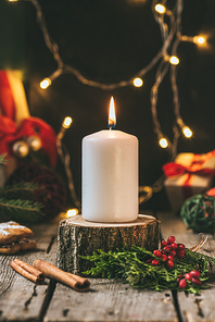 christmas candle on wooden stump with light garland
