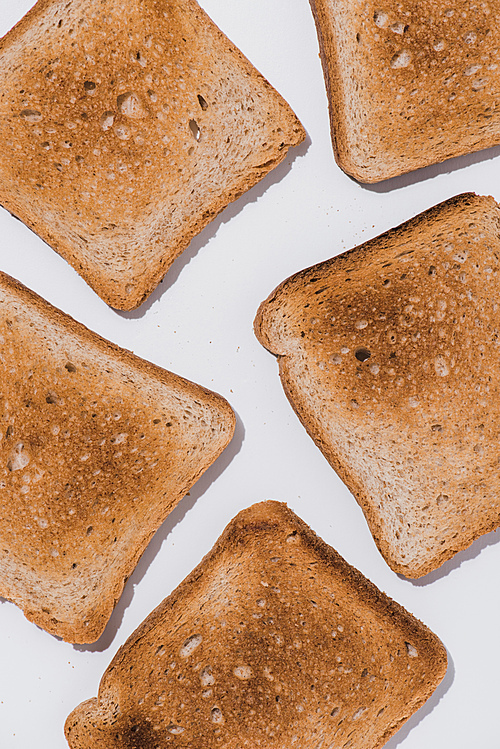 top view of delicious crunchy toasts spilled on white surface