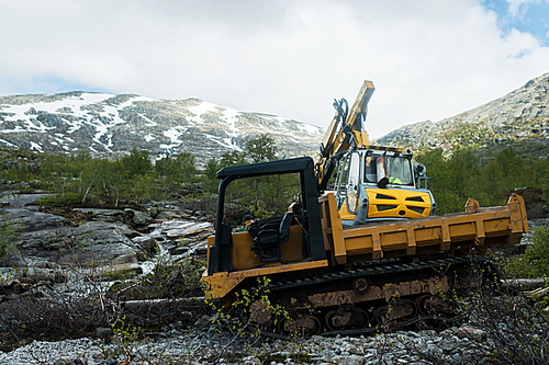 Yellow digger working on a road construction in mountain Norway