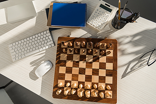flat lay chess board at workplace with computer keyboard