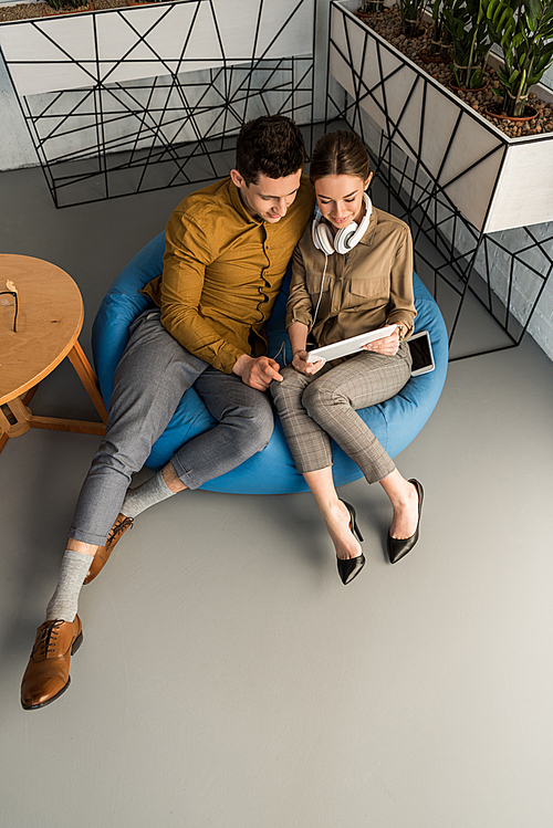 high angle view of young couple using tablet together while sitting in bean bag