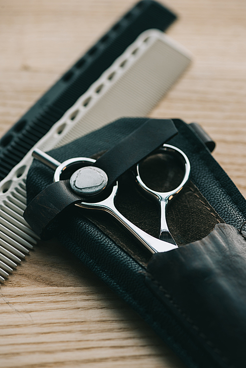 close up view of scissors and combs for hairstyling on wooden tabletop
