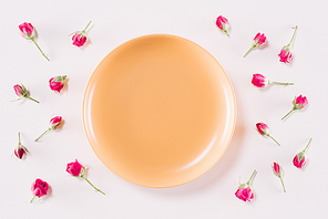 top view of yellow plate and scattered roses isolated on white, valentines day concept